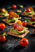 Knusprige Cracker-Häppchen mit Avocado-Creme und Tomaten