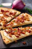 Flammkuchen-Häppchen mit Speck und Zwiebeln.