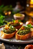 Pesto-Crostini auf einem weißen Teller.