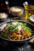 Steinpilz-Pasta mit Parmesan und Rucola auf einem Teller